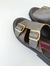 Sandalias de cuero color chocolate con plataforma track negra y hebillas metálicas plateadas.