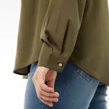 Camisa color verde militar, de corte holgado y manga larga, con cuello camisero y cierre frontal con botones.