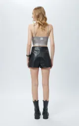 Short negro de cuero sintético con bolsillos laterales y cierres metálicos decorativos en el frente.