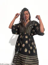 Vestido corto tipo túnica de color negro con estampado de hojas doradas y detalles geométricos.