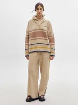 Pantalón de jogging color beige, de corte ancho y suelto, con textura tipo terciopelo y detalle de pespuntes a los lados.