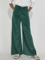 Pantalón de terciopelo gris, de corte palazzo, con bolsillos laterales y cierre frontal con botón y cremallera.