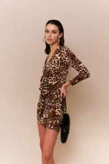 Vestido corto ajustado al cuerpo, con estampado animal print, escote en V, mangas largas y volados frontales.