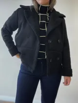 Chaqueta negra con forro tipo corderito, doble botonadura y cuello solapa.