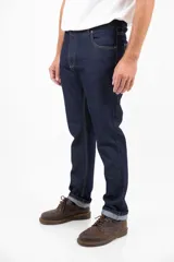 Jean clásico de corte recto, cinco bolsillos, color azul oscuro. Confeccionado en denim de 14 onzas sin elastano, con botones de cobre y costuras color camel.