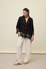 Camisa blanca de calce relajado, con cuello clásico, mangas 3/4 y cierre frontal de botones. Presenta bordados florales en relieve y detalles de crochet calado en los puños y el ruedo.