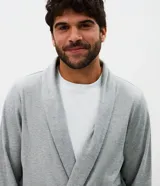 Bata de baño larga de tejido de poliéster texturizado con relieve, cuello estilo chal, mangas largas, bolsillos frontales y lazo para ajustar en la cintura.