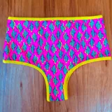 Conjunto de bikini con corpiño triangular estampado con motivos geométricos y bombacha tiro alto color verde liso.