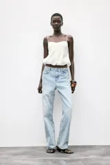 Top corto blanco confeccionado con lino, de tirantes finos, escote pico y espalda abierta con tira elástica horizontal. Tiene bajo abullonado con elástico interior.