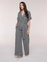 Conjunto de dos piezas de calce fluido y relajado con estampado geométrico en blanco y negro. Incluye una chaqueta con escote en V, solapa, diseño cruzado con lazo y bolsillos con solapa en el pecho, y un pantalón de tiro alto y corte wide leg.