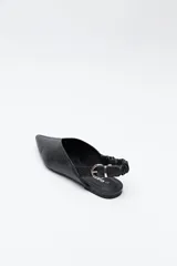 Zapato destalonado de punta fina, color negro, con base baja y tira trasera elástica con hebilla metálica ajustable. Diseño minimalista.