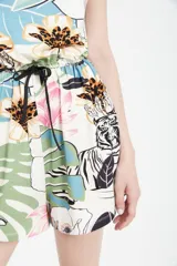 Mono corto con estampado de hojas, flores y tigres en tonos celeste, verde, amarillo y negro. Tiene escote en V, cintura elastizada con cordón y bolsillos laterales.