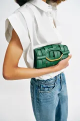 Bolso de mano con diseño de efecto trenzado en color verde, formato rectangular alargado, con asa metálica dorada integrada y cierre mediante doble clip.