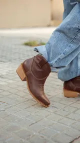 Bota texana corta de cuero color marrón chocolate, con taco de madera y bordados decorativos en el empeine.