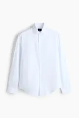 Camisa de vestir H&M de corte entallado, confeccionada en tejido elástico de mezcla de algodón. Presenta cuello italiano, cierre frontal de botones y mangas largas con puños ajustables.