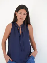 Top sin mangas color azul marino, con escote a la base y detalle de lazos en el cuello.