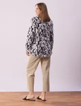 Camisa de lino estampada en blanco y negro con diseño de hojas, marca Zac & Rachel. Tiene cuello con solapa, abertura central con botones, bolsillo aplicado en la parte delantera y mangas largas regulables con presilla y botón.