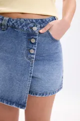 Short pollera de mezclilla en color azul, con diseño cruzado al frente y cierre de botones metálicos.
