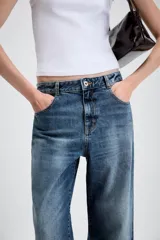Jeans de tiro medio con diseño de cinco bolsillos, pernera holgada y bajo con vuelta. Cierre frontal con cremallera y botón.