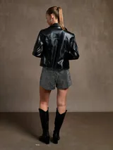 Campera negra de cuero sintético, corte entallado, con cierre frontal y cuello clásico.