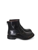 Botín de cuero negro con acabado brillante y efecto desgastado en tonos marrones en la puntera y detalles. Presenta un diseño tipo mocasín con antifaz en el empeine, caña media y cierre posterior.