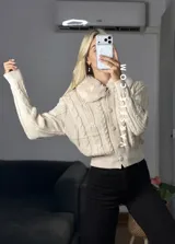 Saco tejido de punto con diseño de ochos, cuello con detalle de piel sintética, cierre frontal con botones al tono y mangas largas.