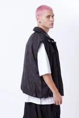 Chaleco negro con estampado de logos, cuello alto, cierre frontal con cremallera y broches a presión ocultos, bolsillos delanteros y cintura ajustable con cordón elástico. Interior de tafeta relleno de guata.