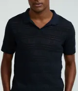 Remera tipo polo de manga corta con cuello en V, confeccionada en un tejido con textura patchwork. Presenta un diseño elegante y versátil, ideal para un look casual o formal.