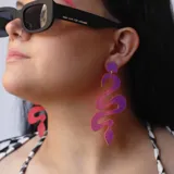 Par de aros colgantes con forma de serpiente, color rojo metalizado.