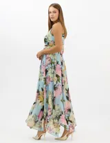 Vestido largo de chifón con estampado floral, cuello halter con pliegues y abertura tipo lágrima. Presenta una cintura drapeada que estiliza la silueta y una falda amplia con capas asimétricas y bajo en picos. Incluye forro interior y cierre invisible en la espalda.