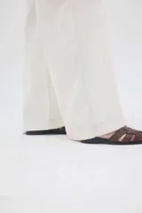 Pantalón jean gris oscuro de tiro medio y piernas anchas, con diseño de cinco bolsillos y cierre frontal con botón y cremallera.