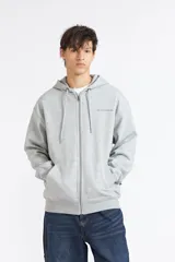 Campera canguro Quiksilver color gris melange con cierre frontal completo, capucha con cordón ajustable, bolsillos tipo canguro y pequeño logo bordado en el pecho.