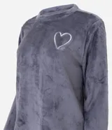 Conjunto de pijama compuesto por una blusa de manga larga en tejido fleece color gris con bordado de corazón en el pecho y un pantalón largo de color blanco con estampado de corazones de colores y cintura elástica.