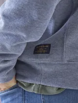 Fleece de algodón color azul, con cuello alto y cierre frontal parcial. Diseño de manga larga con puños y ruedo acanalados.
