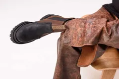 Botas estilo Chelsea de cuero color marrón, con paneles elásticos laterales negros, presillas traseras y suela chunky de goma negra con plataforma dentada.
