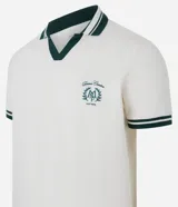 Remera polo comfort color crudo, de manga corta con ribete verde y cuello en V con ribete verde. Tiene un pequeño logo bordado en el pecho.