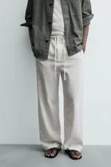 Pantalón de corte regular fit confeccionado en mezcla de algodón y lino. Presenta cintura elástica con cordón ajustable, cierre frontal con cremallera y botón, bolsillos laterales y bolsillo trasero de vivo con botón.