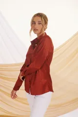 Camisa beige con estampado de líneas diagonales, cuello clásico, cierre con botones y mangas largas con puños abotonados.