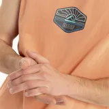 Musculosa color salmón con cuello redondo y sisas amplias. Estampa centrada en el pecho con un diseño de paisaje con palmeras y el texto "Reef".