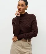 Suéter de punto color crema con textura en zigzag, cuello alto y mangas largas con puños ajustados.