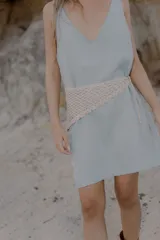 Bandana tejida a crochet con diseño triangular y terminaciones en cordones para anudar. Es un accesorio versátil que puede utilizarse como cinturón o como pañuelo para la cabeza.