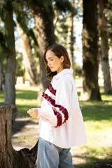 Camisa de lino color rosa claro con corte holgado, cuello camisero y mangas largas. Presenta detalles de volados horizontales en color bordó en el frente y en las mangas.