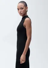 Vestido largo de punto con cuello perkins y diseño sin mangas. Presenta un corte ajustado en el torso que se abre en una falda evasé con textura acanalada en la parte inferior.