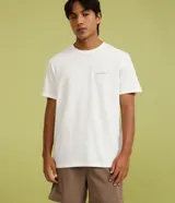Remera masculina comfort de algodón peruano blanco, de cuello redondo y manga corta, con pequeña estampa lettering abstracta en el pecho.