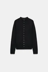 Chaqueta de punto extrafino color negro con cuello redondo y manga larga. Cierre frontal con hilera de botones pequeños.