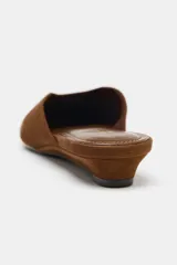 Zapato tipo mule destalonado de ante color marrón, con tacón bajo tipo cuña y punta cuadrada.