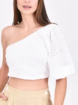 Top blanco con un solo hombro, manga corta abullonada y detalle de calado.