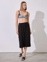 Falda midi negra de modal con pretina ancha elastizada en punto smock, tajo lateral y botones metálicos.