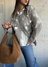 Cardigan de punto color beige con diseño de flores bordadas en relieve, cuello redondo, cierre frontal con botones y puños acanalados.