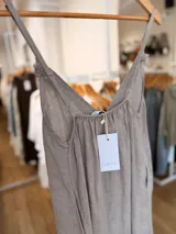 Vestido maxi de lino color blanco, con escote en V, tirantes finos regulables y detalles de flecos en el frente.